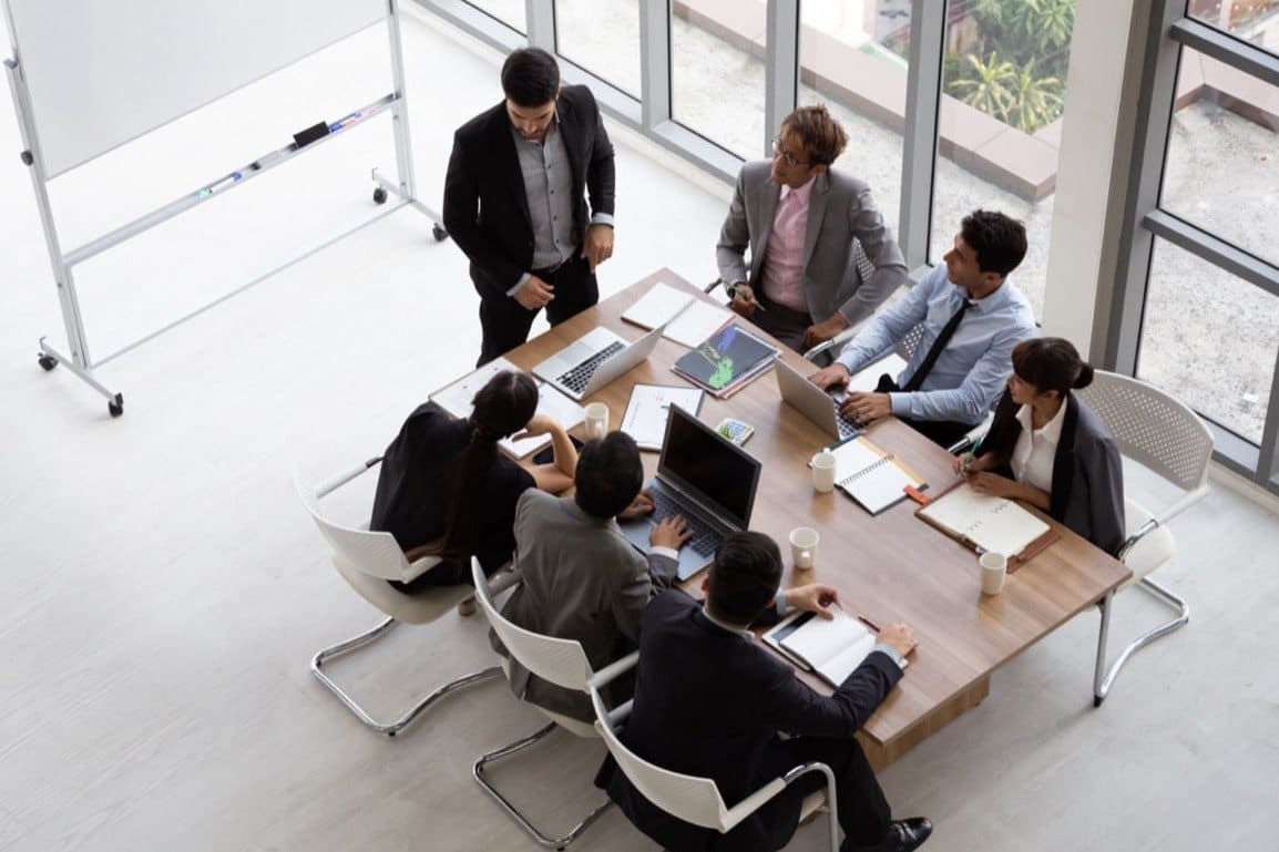 An aerial view of a group of multiethnic people sitting at a desk during an office meeting.